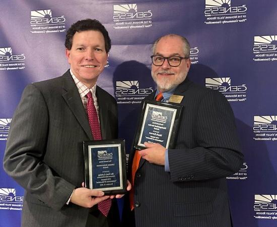 Mark Kovacs and Gary Leising hold up plaques at the Genesis Group's Celebration of Education event in November 2023.